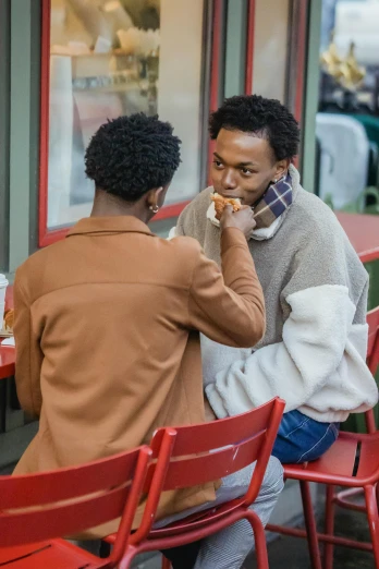 two men sitting at a table eating pizza, trending on unsplash, model wears a puffer jacket, romantic lead, ethiopian, lesbians