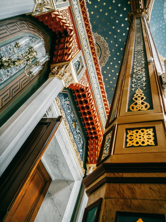 a clock mounted to the side of a building, a detailed painting, by Julia Pishtar, trending on unsplash, arts and crafts movement, mosque synagogue interior, pillars on ceiling, cyan and gold scheme, marble room