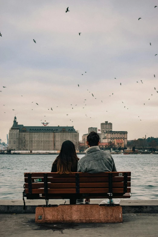 a man and a woman sitting on a bench in front of a body of water, pexels contest winner, romanticism, flying birds in distance, city docks, scandinavian, sittin