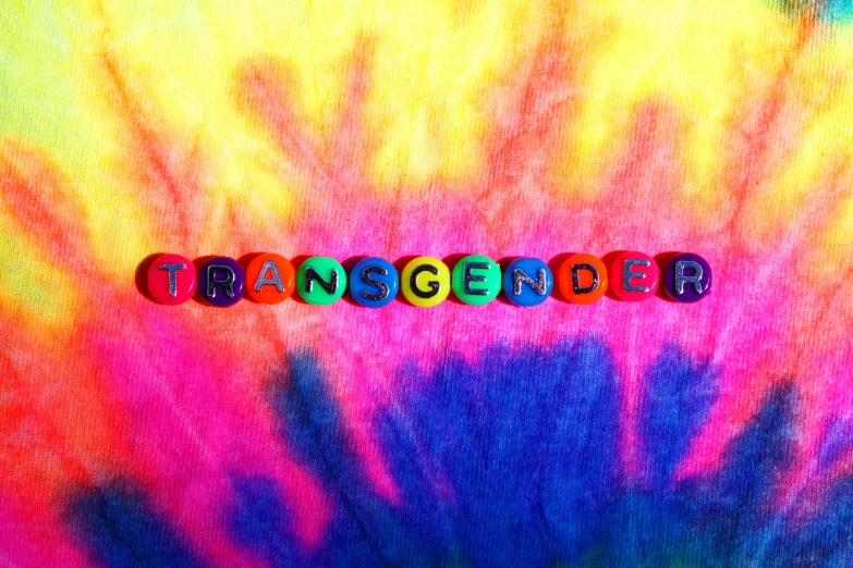 a colorful tie dye background with the word transseber, ambiguous gender, midriff, taken in the late 2010s, up-close