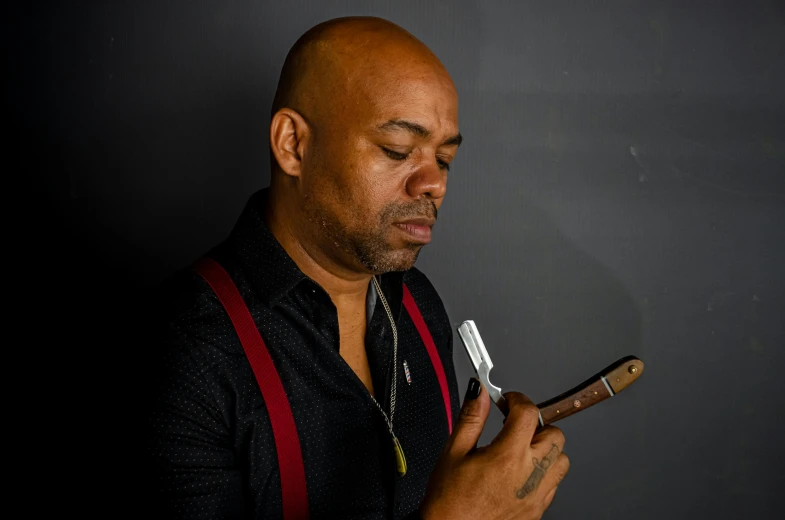 a bald man looking at his cell phone, an album cover, inspired by George Barret, Jr., pexels contest winner, figuration libre, holds a small knife in hand, earl nore, looking to the side off camera, with cigar