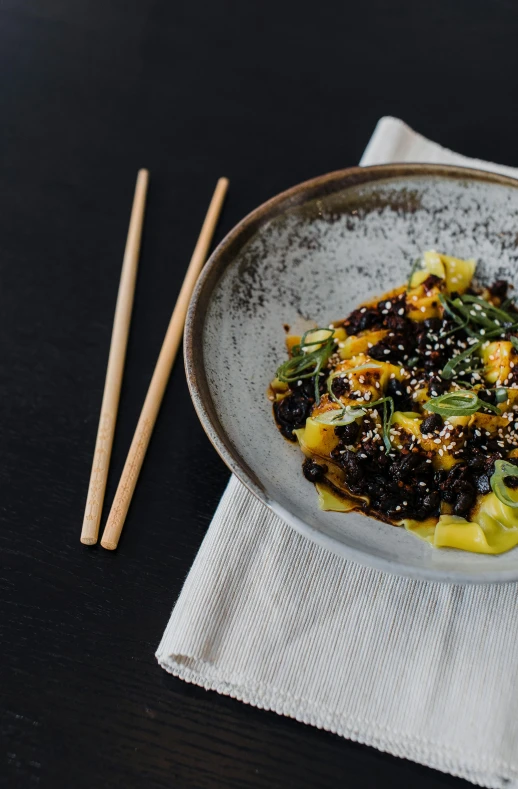 a close up of a plate of food with chopsticks, inspired by Wang Mian, unsplash contest winner, mingei, yellow and charcoal leather, intricate pasta waves, beautiful black blue yellow, black canvas