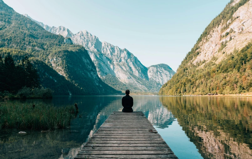 a person sitting on a dock next to a body of water, pexels contest winner, mountains and rivers, meditation, videogame still, headspace