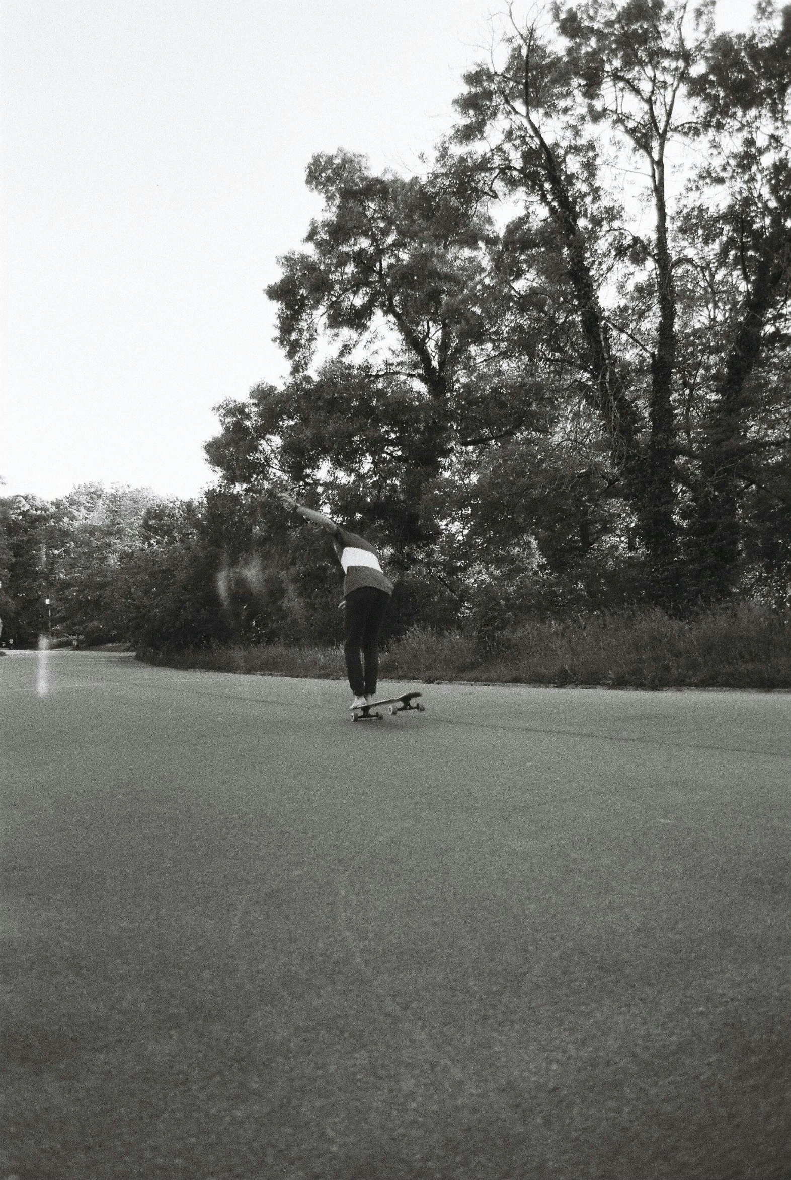 a man riding a skateboard down the middle of a road, a black and white photo, emily rajtkowski, in the park, loish |, hill