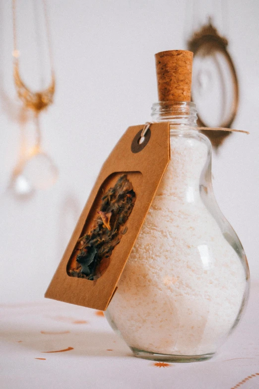 a bottle filled with sand sitting on top of a table, an album cover, by Julia Pishtar, unsplash, renaissance, himalayan rocksalt lamp, detailed white, close-up product photo, organic ornament