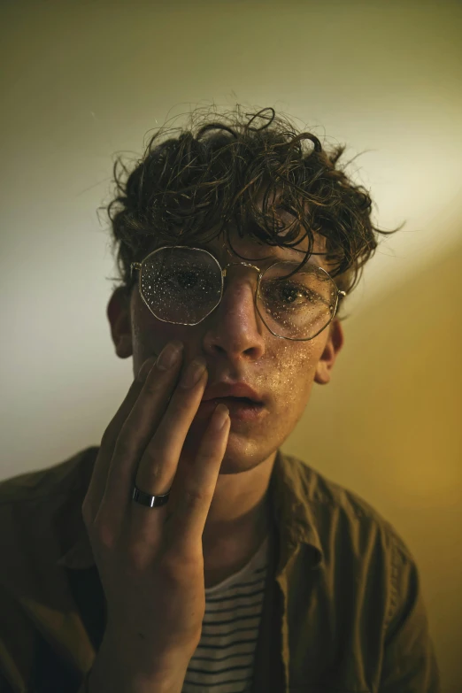 a close up of a person wearing glasses, an album cover, by Jacob Toorenvliet, trending on pexels, hyperrealism, white freckles, teen boy, movie still of a tired, curls on top