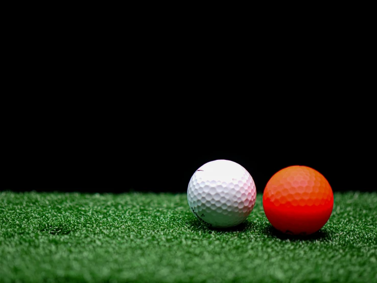 two golf balls sitting on top of a green field, pixabay, dark orange black white red, indoor shot, red and white neon, face shot