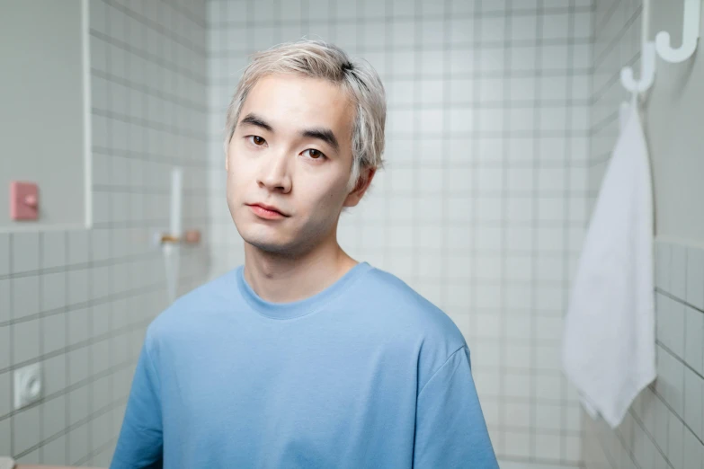 a man in a blue shirt standing in a bathroom, a character portrait, unsplash, shin hanga, platinum hair, aged 2 5, ignant, ethnicity : japanese