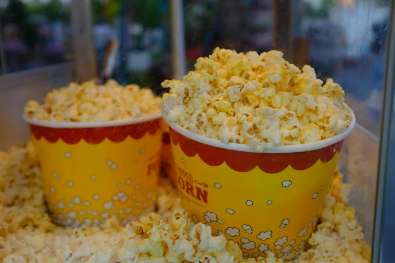 two buckets of popcorn sitting next to each other, by Adam Marczyński, pexels, square, yellow, market, bowl filled with food