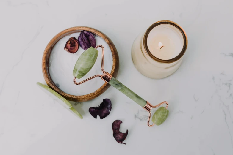 a wooden bowl sitting on top of a table next to a candle, green facemask, copper and emerald, clean face and body skin, product view