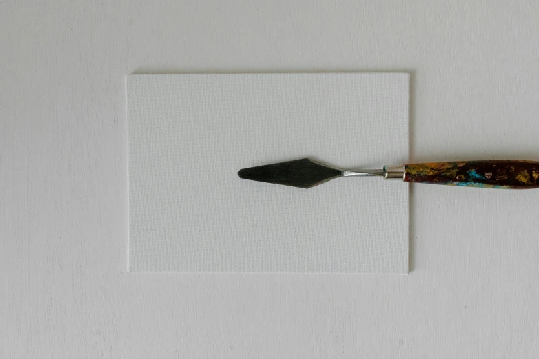 a knife sitting on top of a piece of paper, a minimalist painting, inspired by Kyffin Williams, visual art, spatula, white finish, white wall coloured workshop, fan favorite