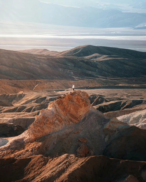 a person standing on top of a mountain, unsplash contest winner, process art, death valley, earthy colours, high view, rocky hills