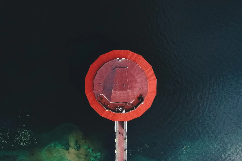 a large red object in the middle of a body of water, by Jesper Knudsen, pexels contest winner, hurufiyya, helipad, orange roof, down there, near a jetty