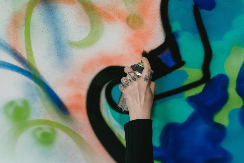 a person spraying graffiti on a wall with a spray can, an airbrush painting, by Julia Pishtar, trending on pexels, point finger with ring on it, carrying a bottle of perfume, silver and cool colors, multi - coloured