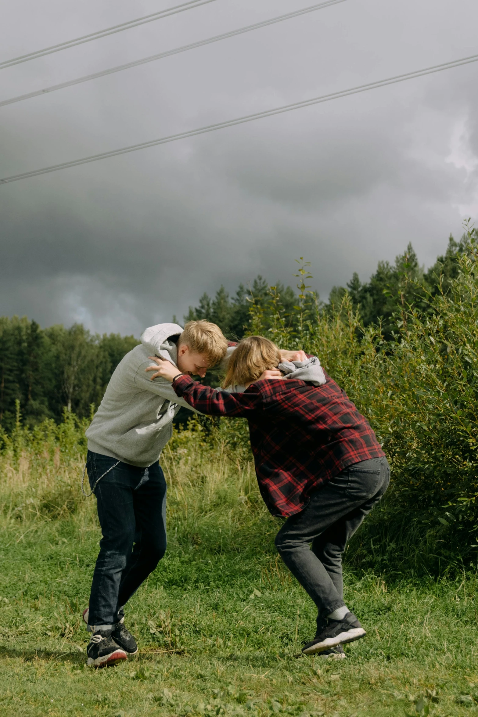 a couple of people standing on top of a lush green field, fighting each other, in russia, non-binary, during a storm