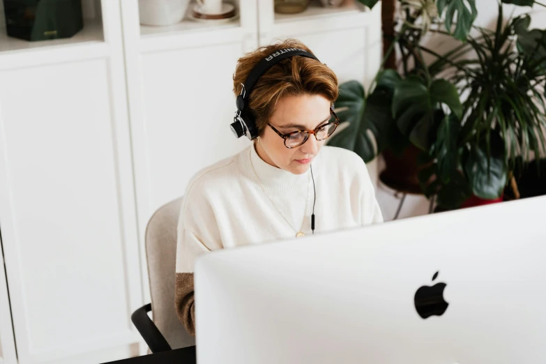 a woman sitting in front of a computer wearing headphones, by Julia Pishtar, trending on pexels, wearing square glasses, thumbnail, high quality image, 1 2 9 7