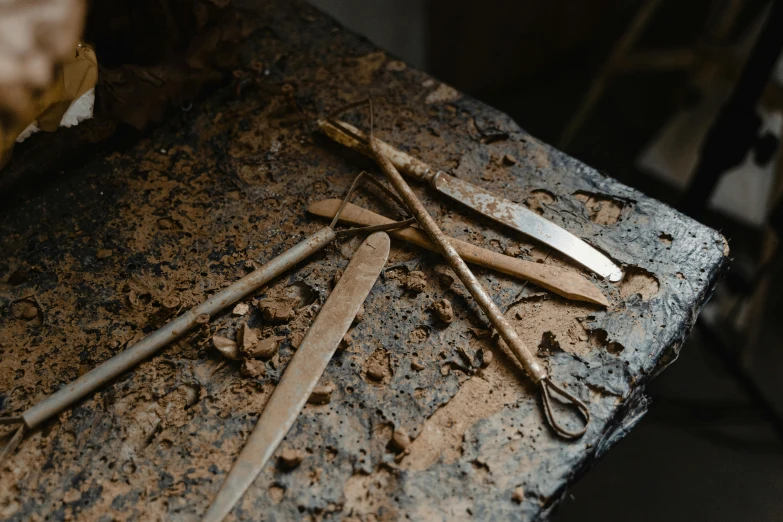 a bunch of tools sitting on top of a table, by Thomas Furlong, trending on pexels, arte povera, found in a cave made of clay, burnt umber, made of polished broze, close-up product photo