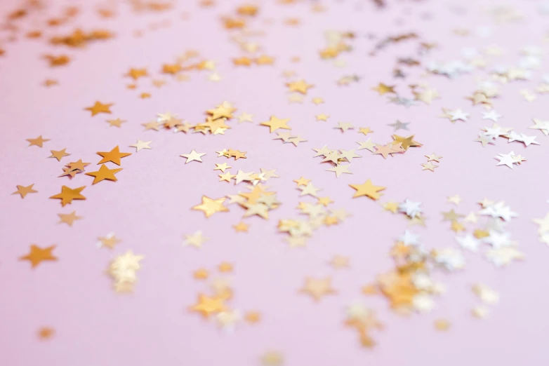 a pink table topped with lots of gold stars, trending on pexels, visual art, silver，ivory, background image, spangle, starlight