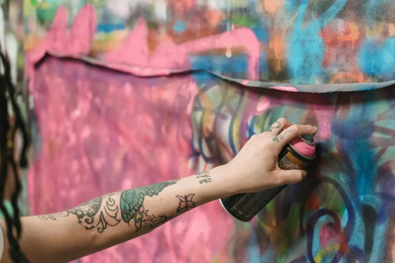 a person spraying graffiti on a wall with a spray can, trending on pexels, graffiti, body covered in floral tattoos, rainbow splash of ink, photograph of a sleeve tattoo, pink and blue and green mist