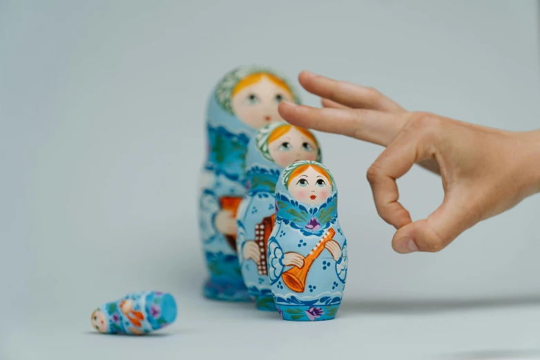 a hand reaching for a russian nesting doll, by Aleksandr Gerasimov, trending on unsplash, interactive art, blues, musician, miniature porcelain model, kid named finger