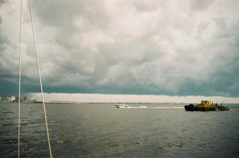 a boat on a body of water under a cloudy sky, rainy; 90's photograph, joel sternfeld, 2000s photo