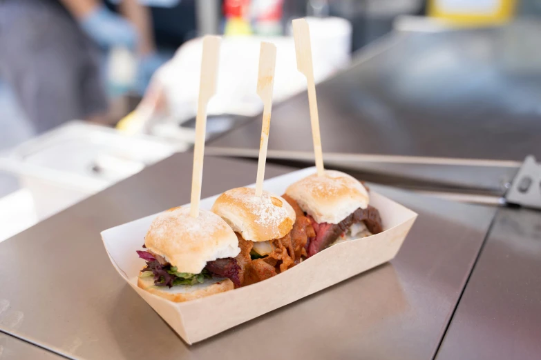 a couple of sandwiches sitting on top of a table, skewer, carrying a tray, melbourne, fair