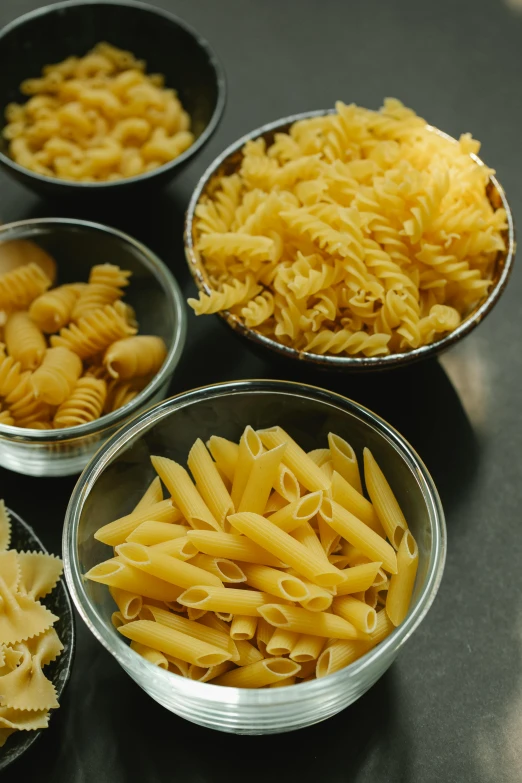 a table topped with bowls filled with different types of pasta, medium detail, different sizes, 6 pack, 4l