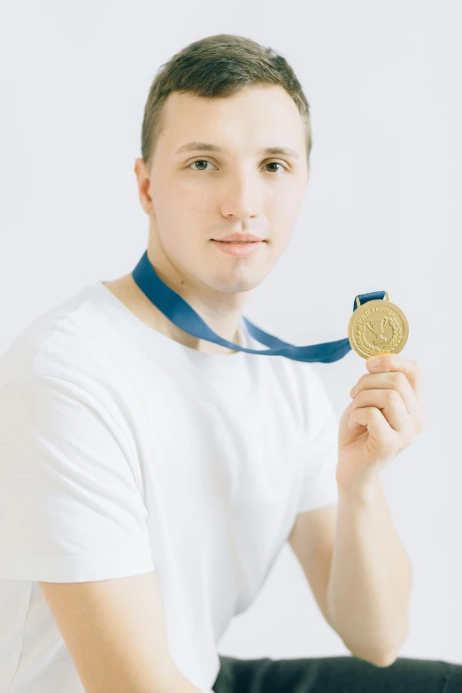 a man in a white shirt holding a gold medal, inspired by Ryan Pancoast, pexels contest winner, headshot profile picture, high key, wearing a tracksuit, yulia nevskaya