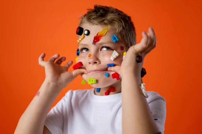 a young boy with paint all over his face, an album cover, inspired by Damien Hirst, trending on pexels, lego set, candy treatments, voxel art, blippi