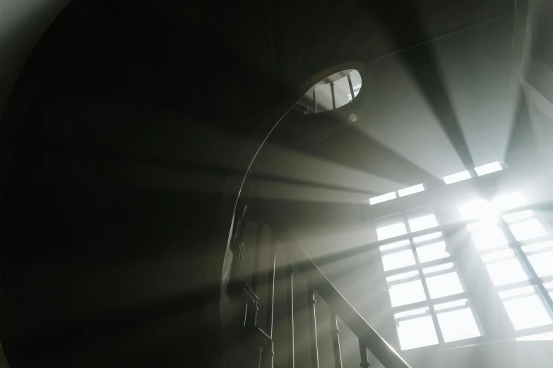 the sun shines through the window of a spiral staircase, pexels contest winner, light and space, dark hazy room, light breaks through the roofs, natural prison light, shot from a low angle