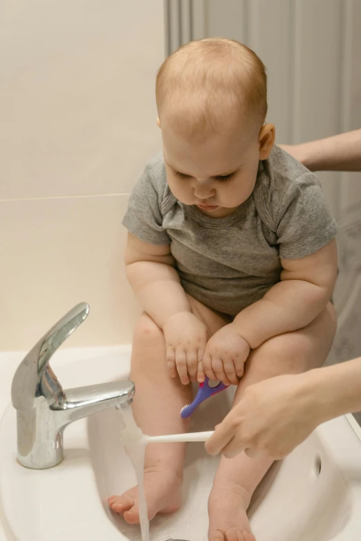 a woman washes a baby's feet in a sink, embarrassed, short spout, smooth feature, thumbnail