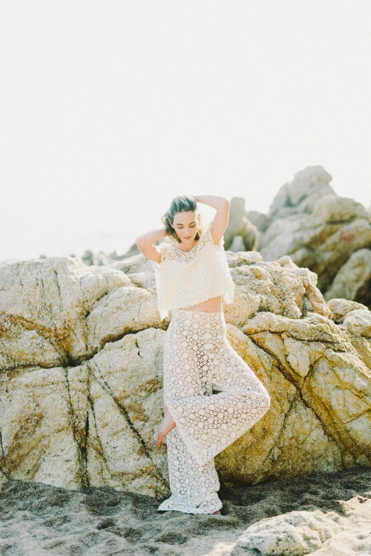 a woman standing on top of a large rock, by Dulah Marie Evans, unsplash, arabesque, translucent skin, wearing a cropped top, coastal, various posed