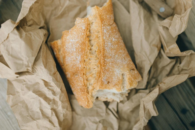 a bag of bread sitting on top of a wooden table, unsplash, background image, baking french baguette, cream paper, thumbnail