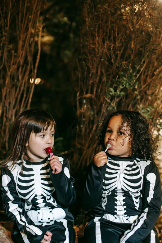 two little girls dressed up in skeleton costumes, by Ellen Gallagher, pexels contest winner, an ewok eating a lollipop, black an white, nigth, ivy's