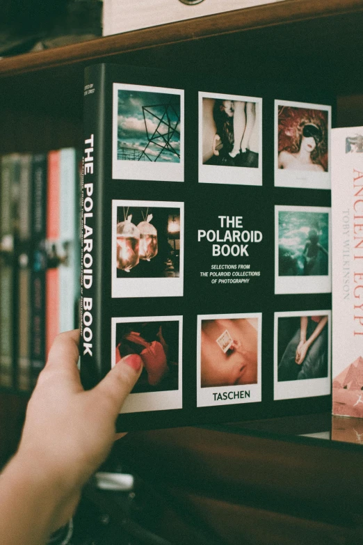 a person holding a book in front of a bookshelf, a polaroid photo, pexels contest winner, photorealism, old photobook, thumbnail, polariod, book cover