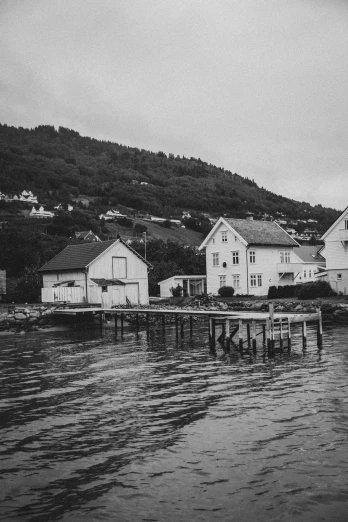 a black and white photo of houses on the water, inspired by Oluf Høst, unsplash, small settlements, concert, 1900s photo, 1980s photograph