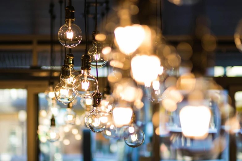 a bunch of light bulbs hanging from a ceiling, by Jesper Knudsen, pexels, light and space, cafe lighting, softly - lit, an upright lightbulb, vibrant scene