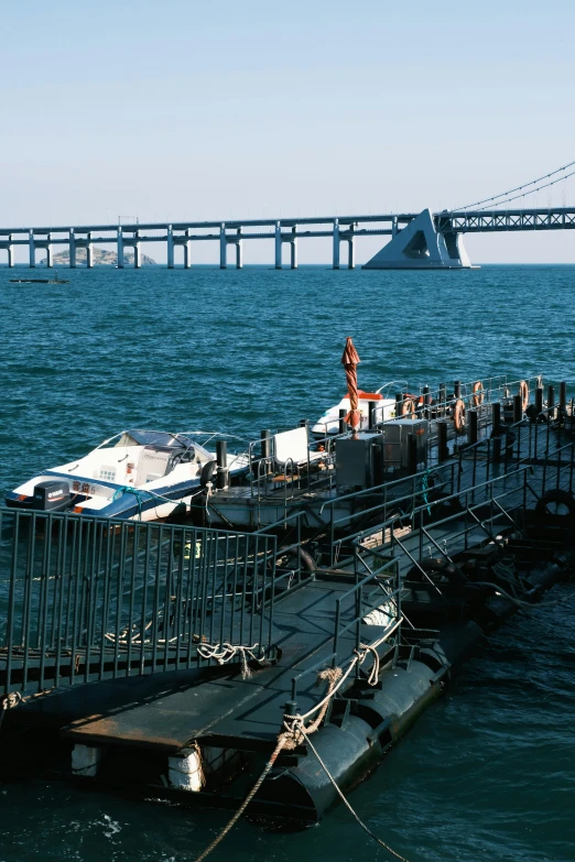 a large body of water with a bridge in the background, an album cover, destroyed ship, 1980s photograph, slide show, 2022 photograph