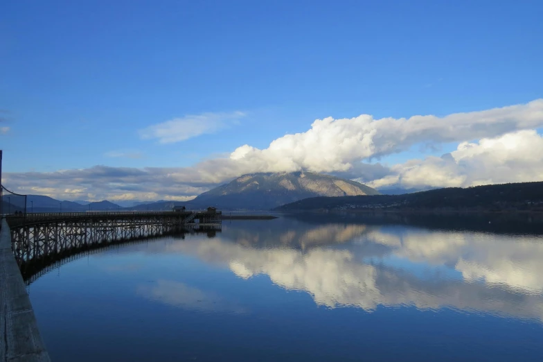 a large body of water with mountains in the background, by Jim Nelson, pexels contest winner, blue reflections, liz truss, cloud day, january