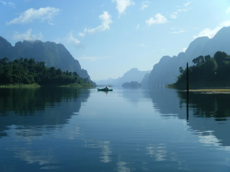 a boat on a body of water with mountains in the background, inspired by Steve McCurry, pexels contest winner, sumatraism, european river, phuoc quan, south east asian with long, blues