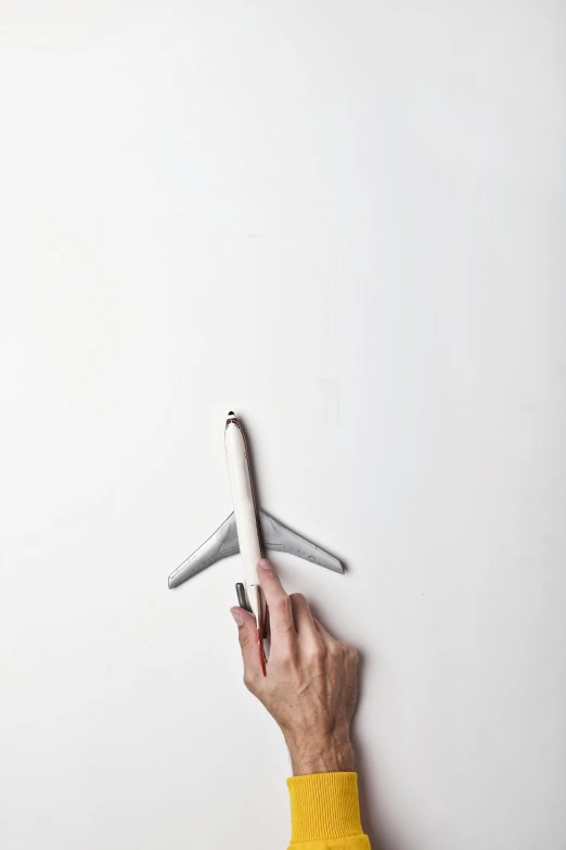 a hand holding a model airplane against a white wall, trending on unsplash, conceptual art, holding pencil, 15081959 21121991 01012000 4k, wallpaperflare, artistic pose