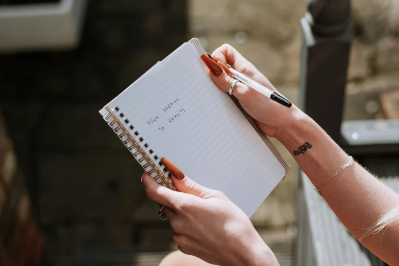 a close up of a person holding a notebook, by Emma Andijewska, pexels contest winner, hidden message, fine point pen, instagram post, without text