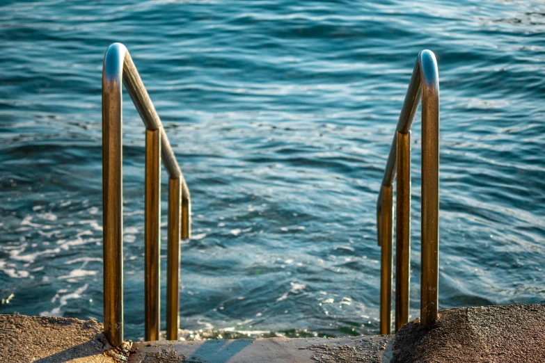 a set of stairs leading to the ocean, by Niko Henrichon, unsplash, happening, stainless steel, realistic water, gold and blue, thumbnail