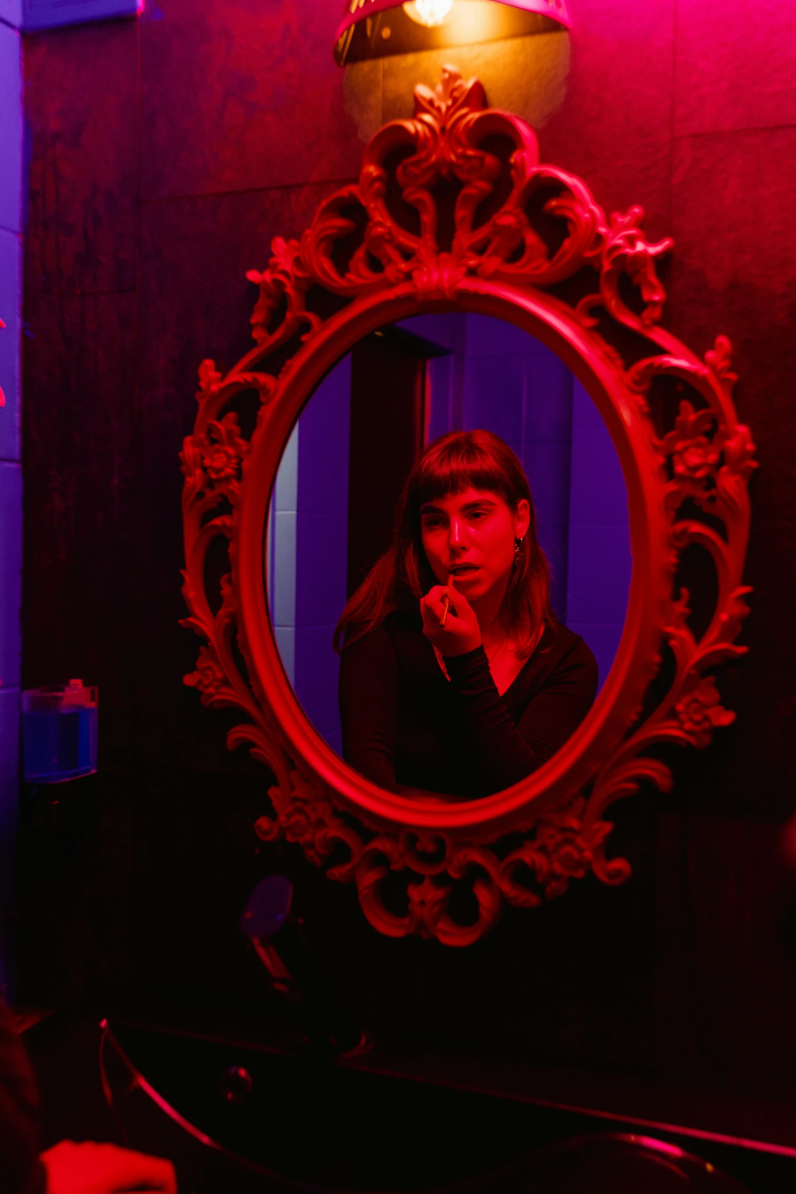 a woman taking a picture of herself in a mirror, inspired by Elsa Bleda, conceptual art, red neon, goth, purple and red, blue room