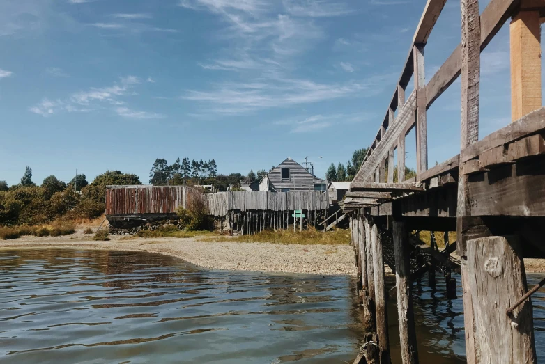 a wooden bridge over a body of water, a portrait, by Jessie Algie, unsplash, hurufiyya, old buildings, kahikatea, peter sculthorpe, seen from outside