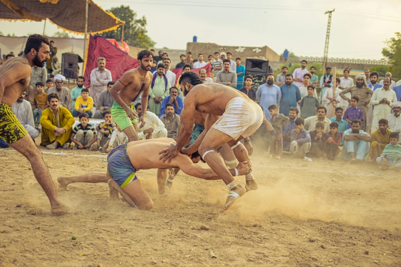 a group of men playing a game of wrestling, an album cover, pexels contest winner, kerala village, dust in the air, in the middle of an arena, thumbnail
