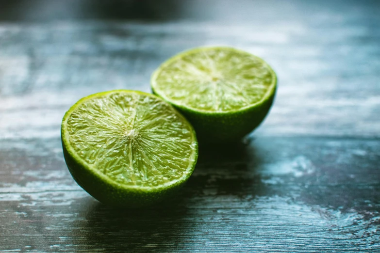 a couple of limes sitting on top of a wooden table, pexels, avatar image, background image, profile pic, crisp focus