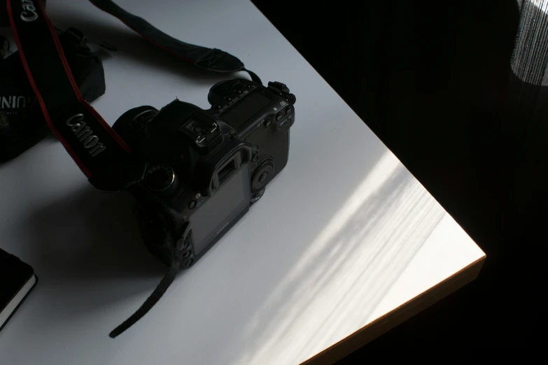 a camera sitting on top of a table next to a cell phone, a photorealistic painting, by Andries Stock, unsplash, back lit lighting, dusty volumetric light, medium format. soft light, on a white table