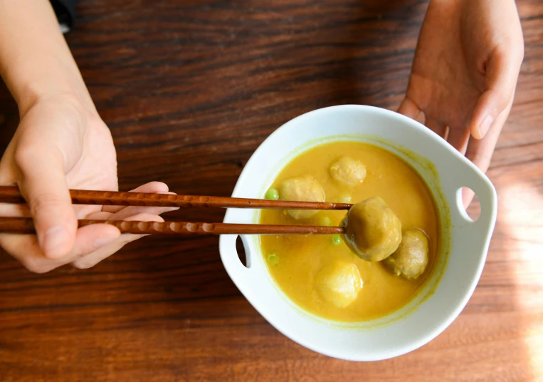 a person holding chopsticks over a bowl of soup, yellow, square, image, fan favorite