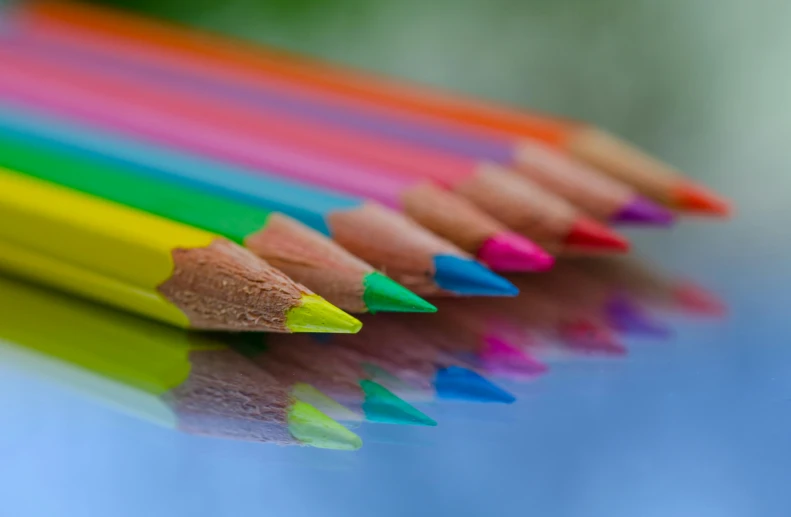 a group of colored pencils sitting on top of a table, by Jan Rustem, pexels contest winner, reflections and refractions, chartreuse and orange and cyan, up close picture, pink and blue colour